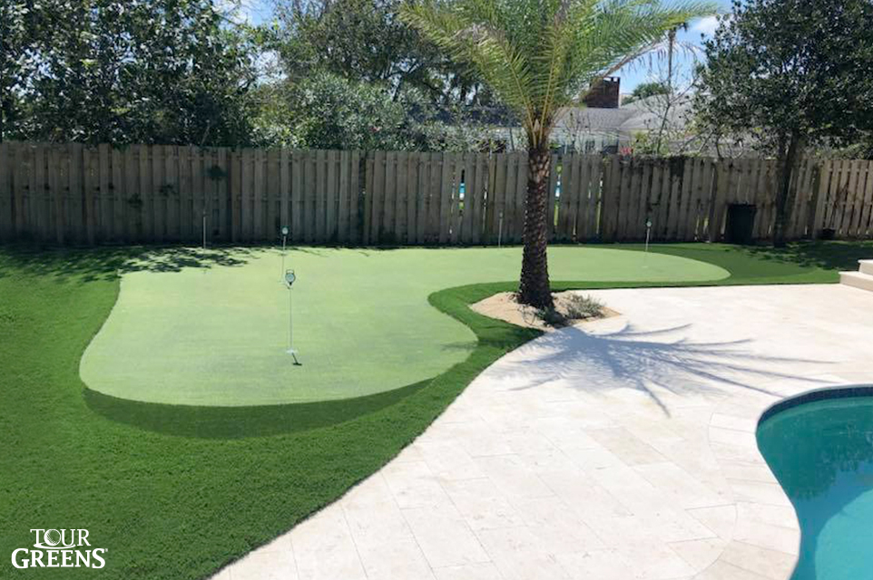 Putting green next to a backyard pool