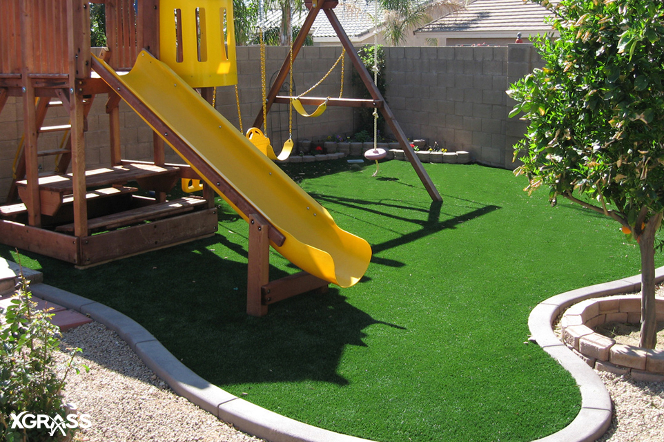 Small backyard with artificial grass lawns underneath the playground set