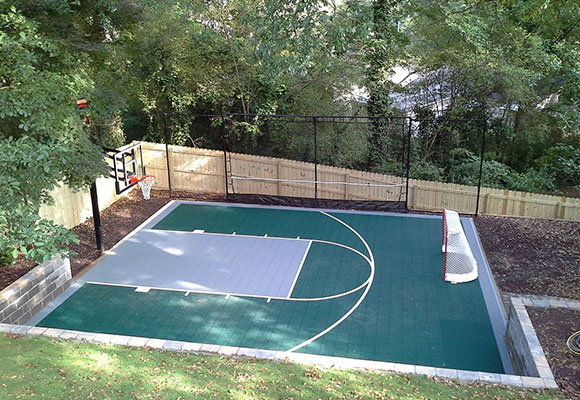 game court with basketball goal and hockey net built into backyard