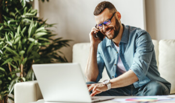 person talking on the phone while looking at his laptop