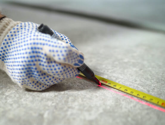 using a measuring tape and marker to measure space intended for a game court