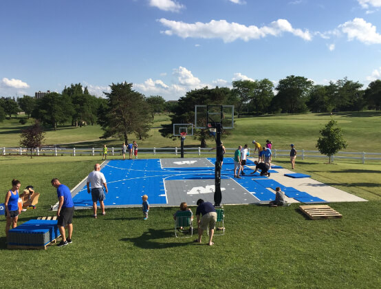 large group of people working together to assemble tile court on an outdoor field