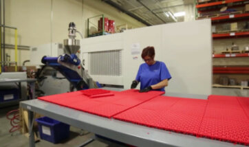 a woman manually inspects court tiles for quality assurance