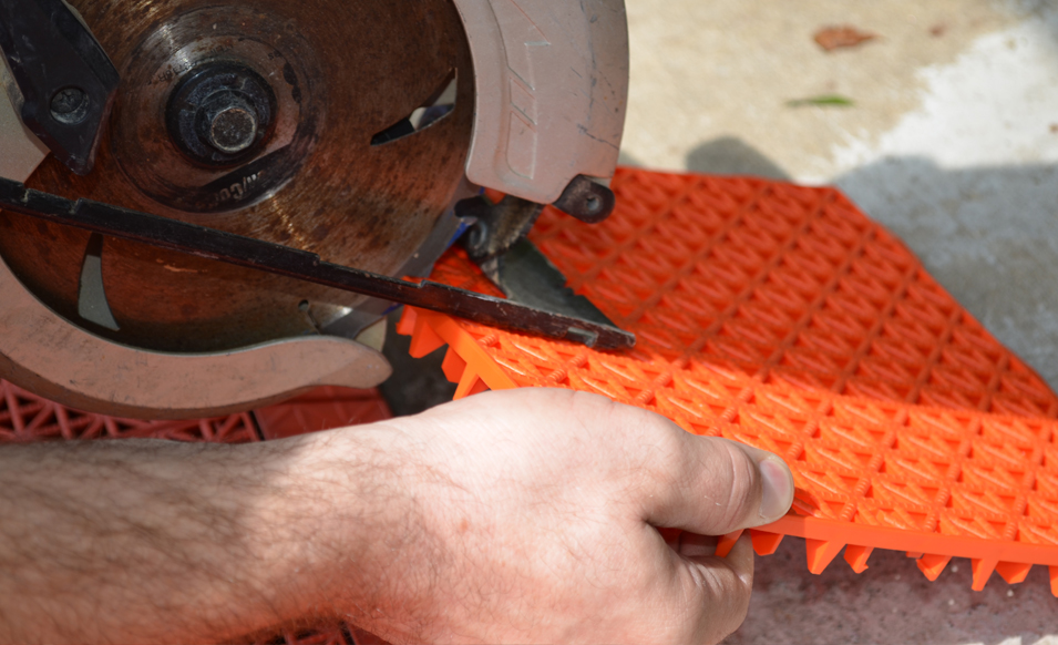 Trimming orange game tile with hand-held circular saw